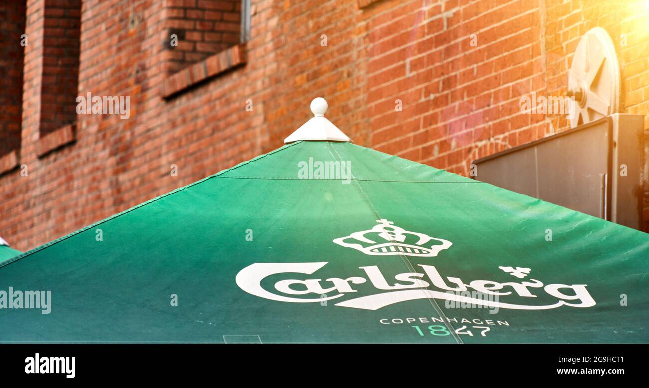 Carlsberg-Schriftzug und Logo der dänischen Brauerei auf einem grünen  Sonnenschirm vor einer Backsteinfassade in Hamburg, 22. Juli 2021  Stockfotografie - Alamy