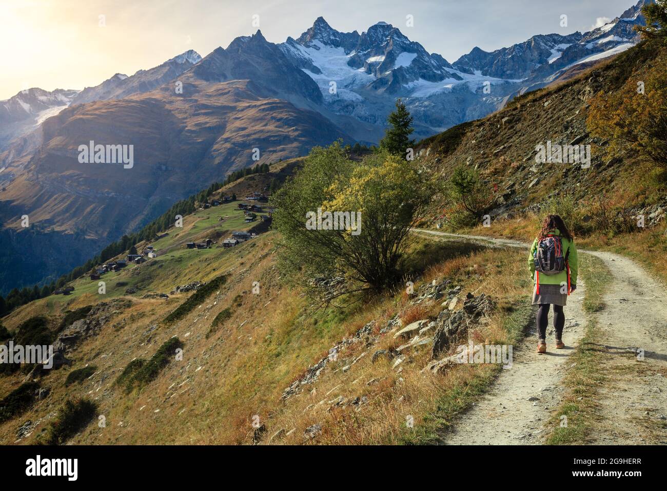 Junge Frau, die in der Nähe der Schweizer Kurstadt Zermatt auf einem Wanderweg in den Bergen spazierengeht Stockfoto