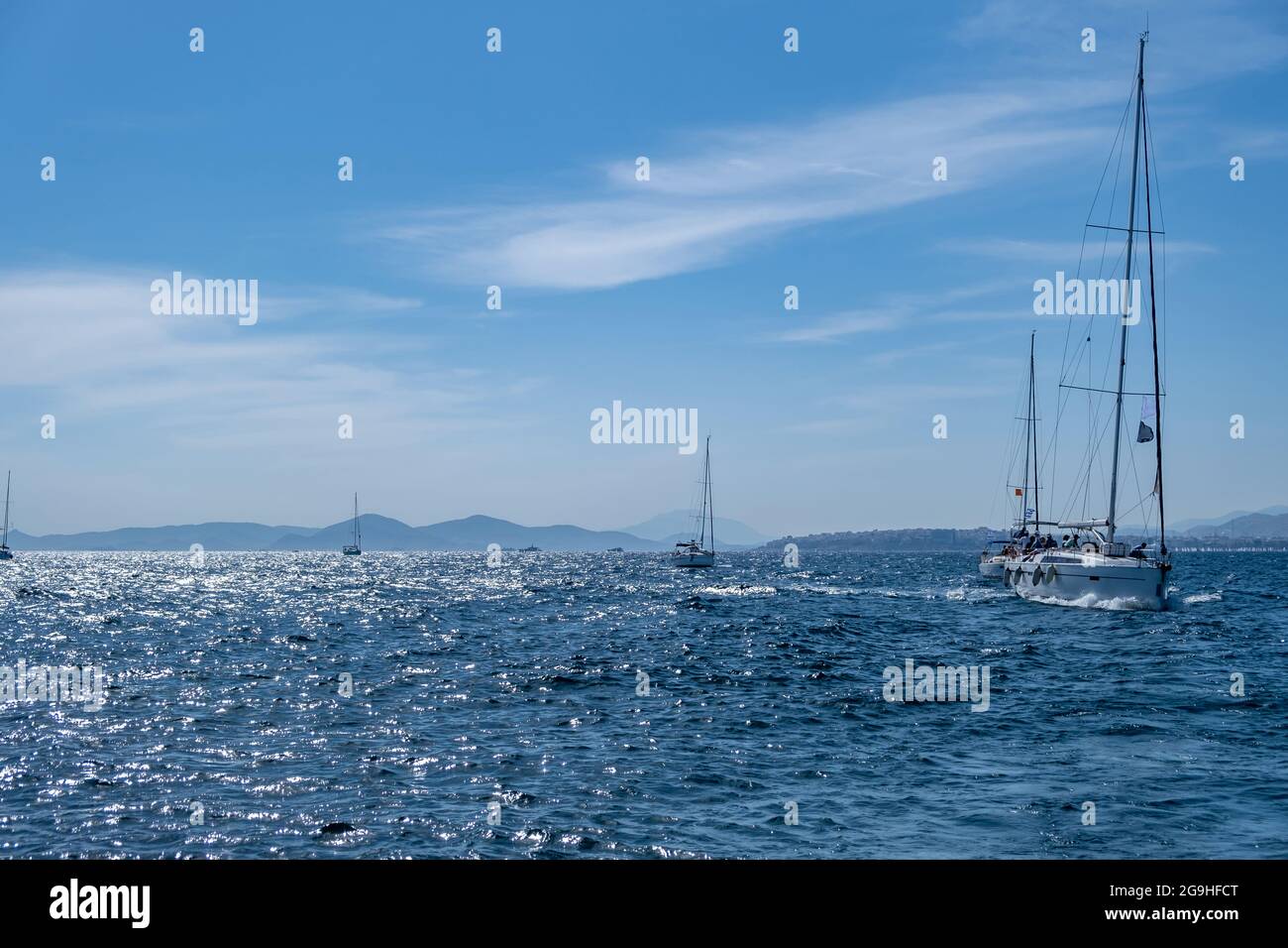 Segeln in der Ägäis Griechenland. Segelboote mit offenen weißen Segeln, die auf dem welligen Meer kreuzen, blauer Himmel im Hintergrund, sonniger Tag. Sommerurlaub in Kykladen ist Stockfoto