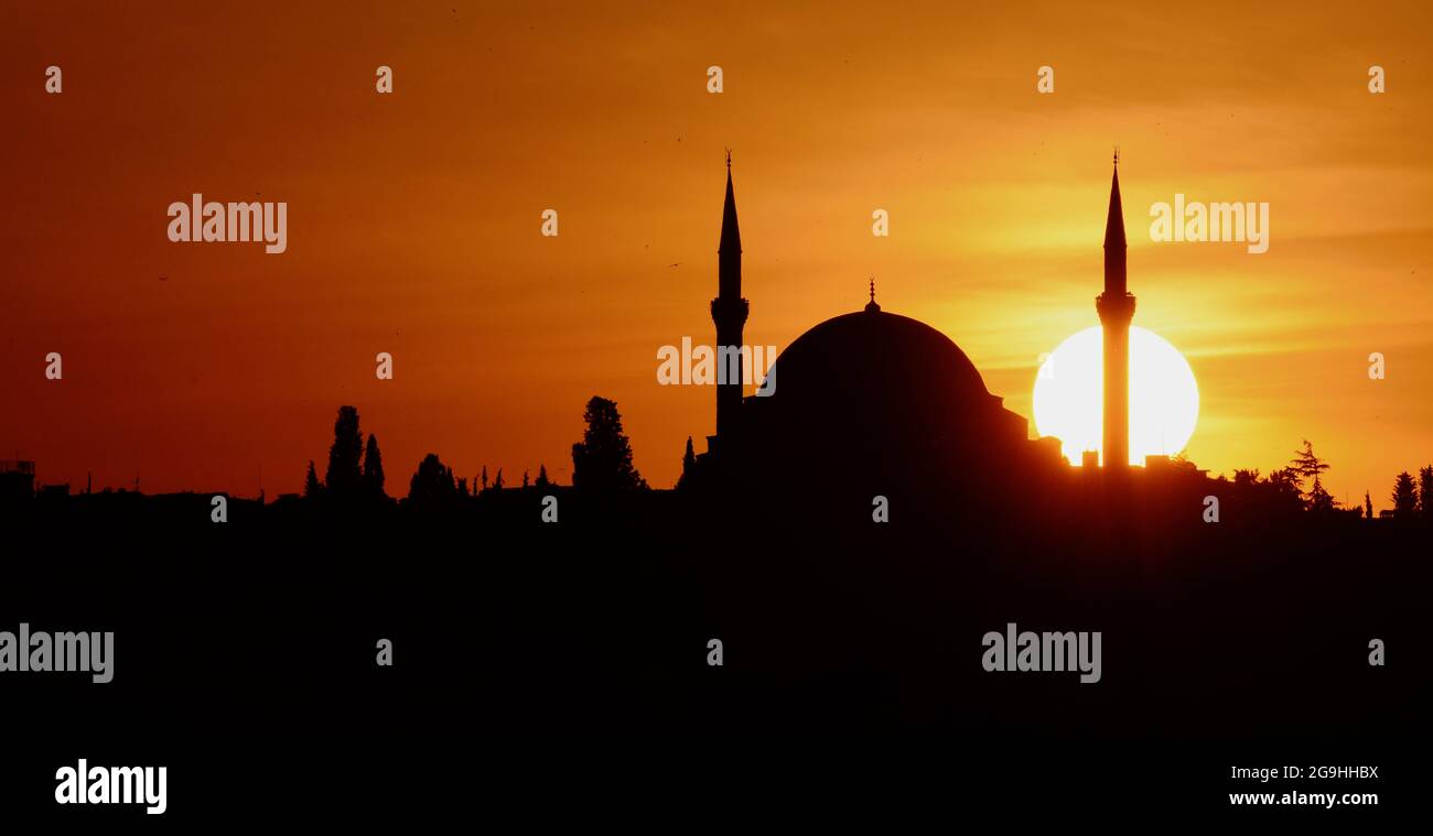 Atemberaubender goldener Sonnenuntergang über der Skyline von Istanbul, Silhouette einer Moschee-Kuppel und Minarette mit heller, kreisförmiger Sonne. Stockfoto