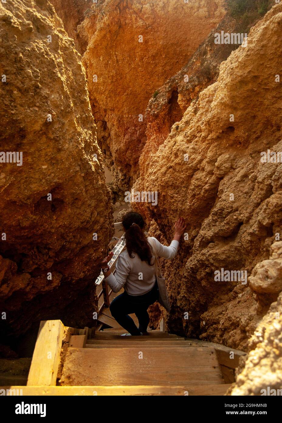 Frau, die den schmalen Weg zwischen den Felsen hinuntergeht Stockfoto