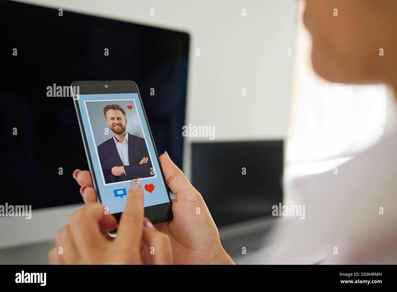 Frau mit Mobiltelefon und Blick auf das Bild des jungen Mannes auf der Online-Dating-App Stockfoto