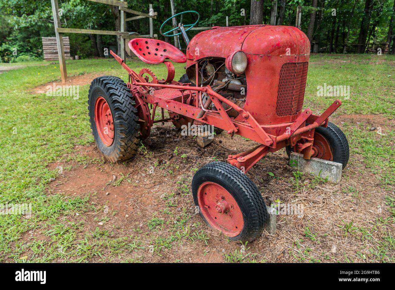 Alte antike kleine rote Bauernhof Traktor auf dem Feld auf einem Bauernhof für die Anzeige im Freien Winkel Ansicht Nahaufnahme geparkt Stockfoto