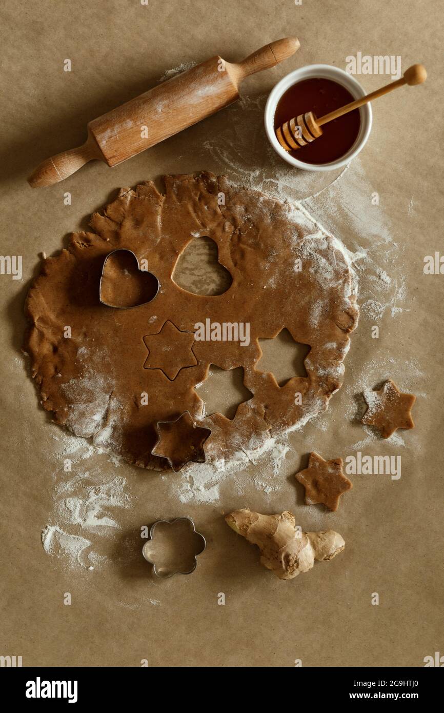 Weihnachten hausgemachte Lebkuchenkekse auf einem braunen Papier, Honig, Nudelholz Draufsicht. Festliche hausgemachte Lebkuchenkekse. Traditionelles Weihnachtskekchen Stockfoto