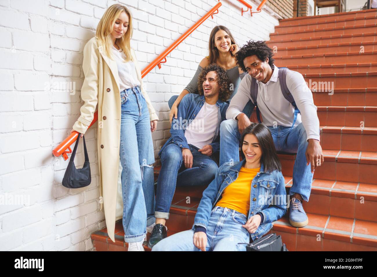 Eine Gruppe von Studenten mit ethnischer Vielfalt, die auf einigen Stufen auf der Straße sitzen und Spaß miteinander haben. Stockfoto