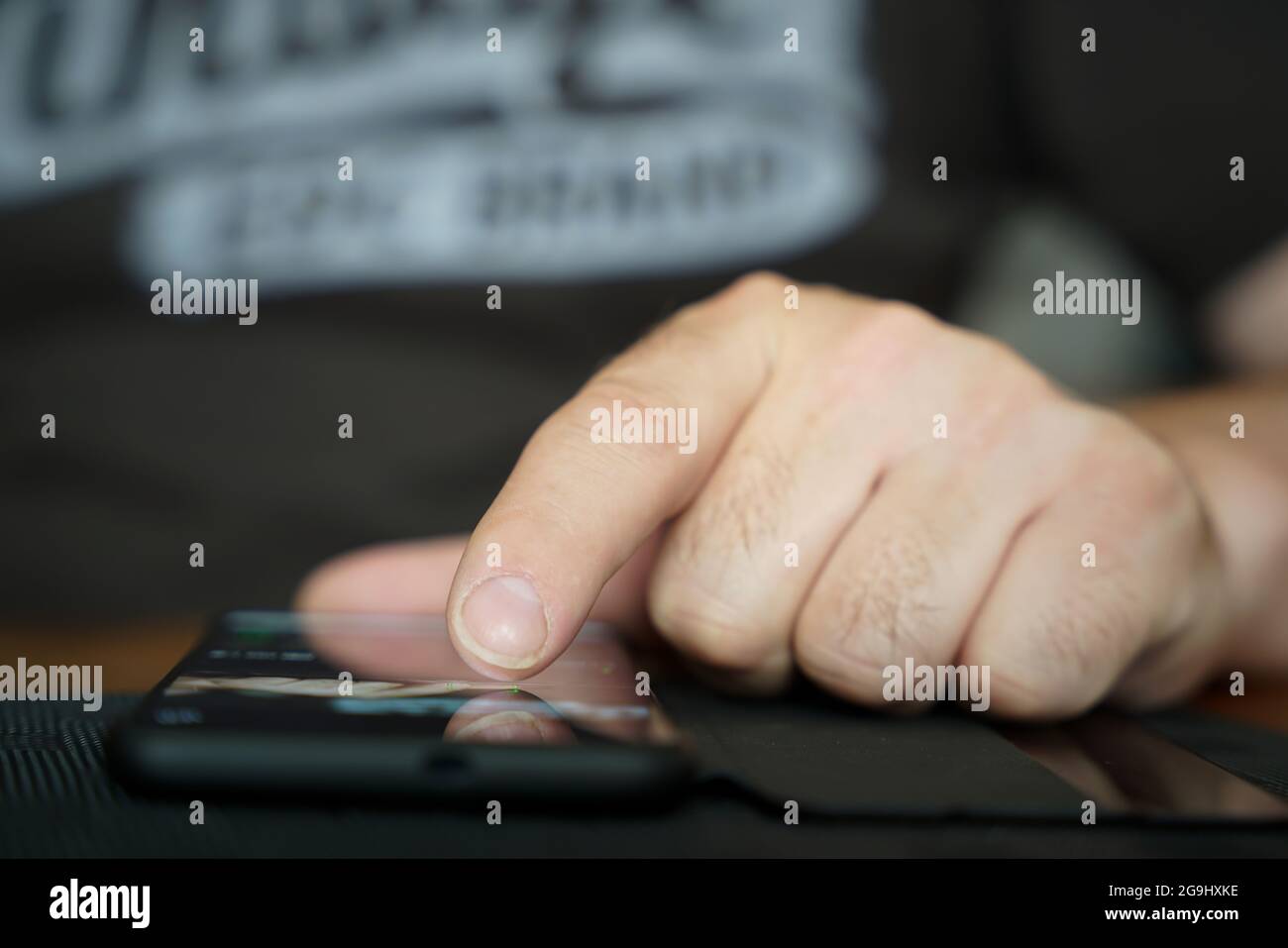 Finger einer Person bedienen ein Smartphone, das auf dem Tisch liegt, und wählen eine App aus Stockfoto