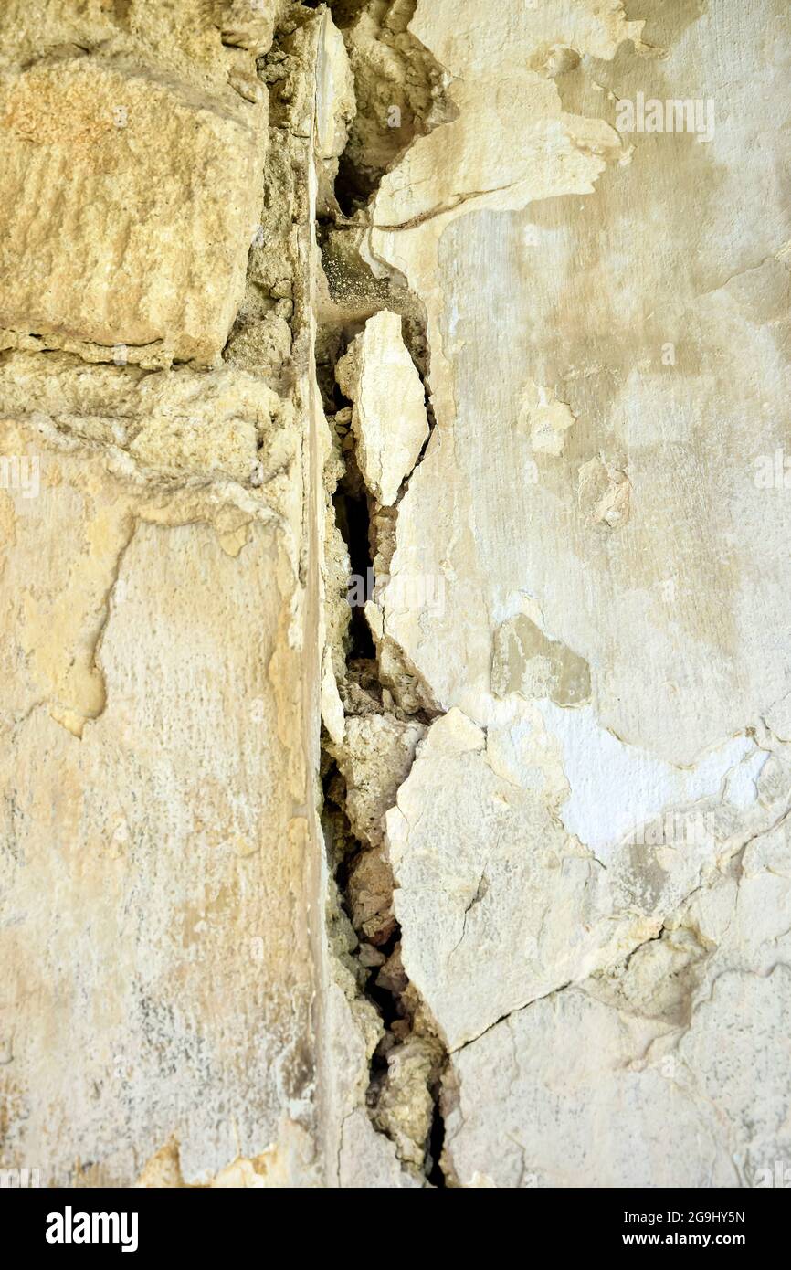 Großer Riss an der grauen Wand des alten Gebäudes, abstraktes Bild des vertikalen Risses, Detail. Folgen des Erdbebens. Speicherplatz kopieren. Selektiver Fokus. Stockfoto Großer Riss an der grauen Wand des alten Gebäudes, abstraktes Bild des vertikalen Risses, Detail. Folgen des Erdbebens. Speicherplatz kopieren. Selektiver Fokus. Stockfoto