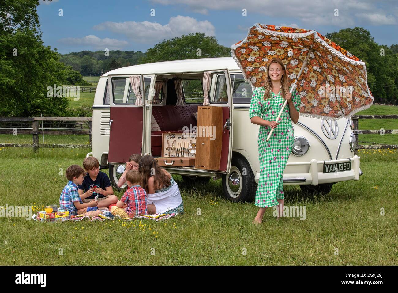Familie auf Woodfire Camping bei Petworth in West Sussex mit einem VW-Wohnmobil im Retro-Stil von 1966, England, Großbritannien Stockfoto