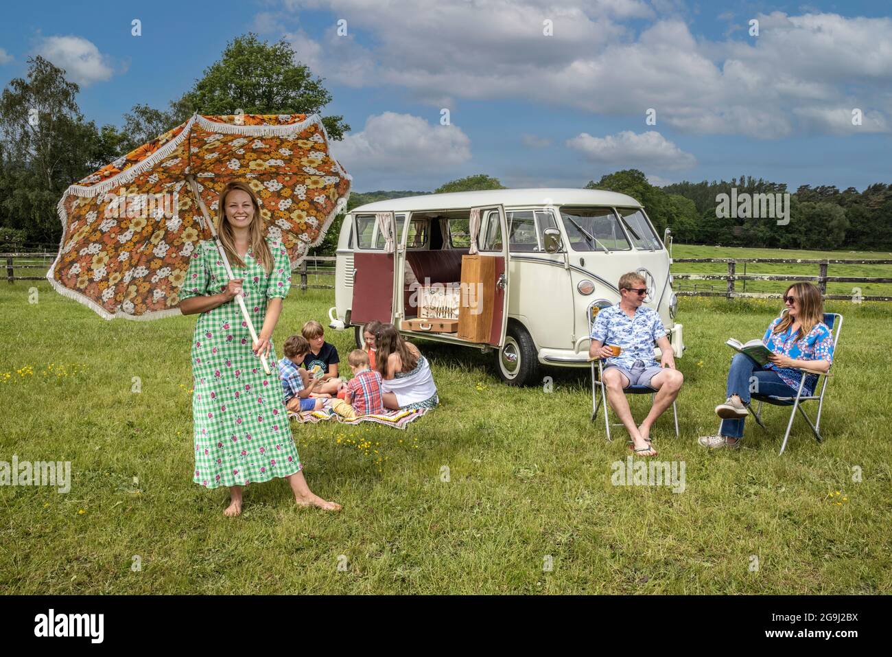 Familie auf Woodfire Camping bei Petworth in West Sussex mit einem VW-Wohnmobil im Retro-Stil von 1966, England, Großbritannien Stockfoto