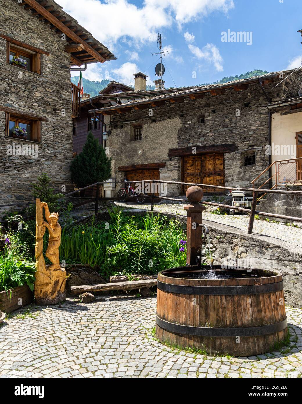 Ein Brunnen zwischen typischen alpinen Häusern in Pontechianale, Varaita-Tal, Piemont, Italien Stockfoto