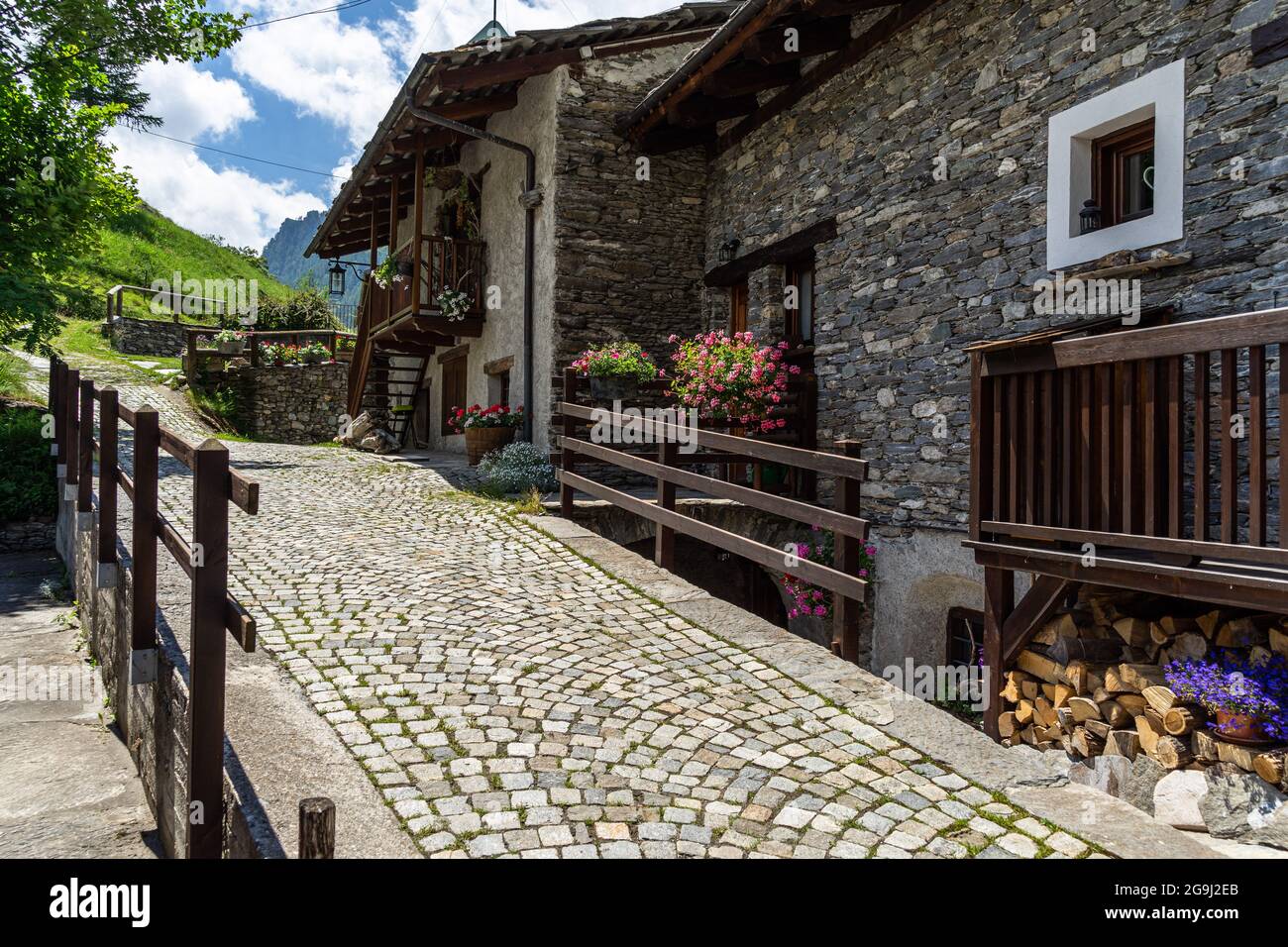 Eine gepflasterte Straße und alpine Häuser in Pontechianle, einem charmanten Dorf im Varaita-Tal, Piemont, Italien Stockfoto