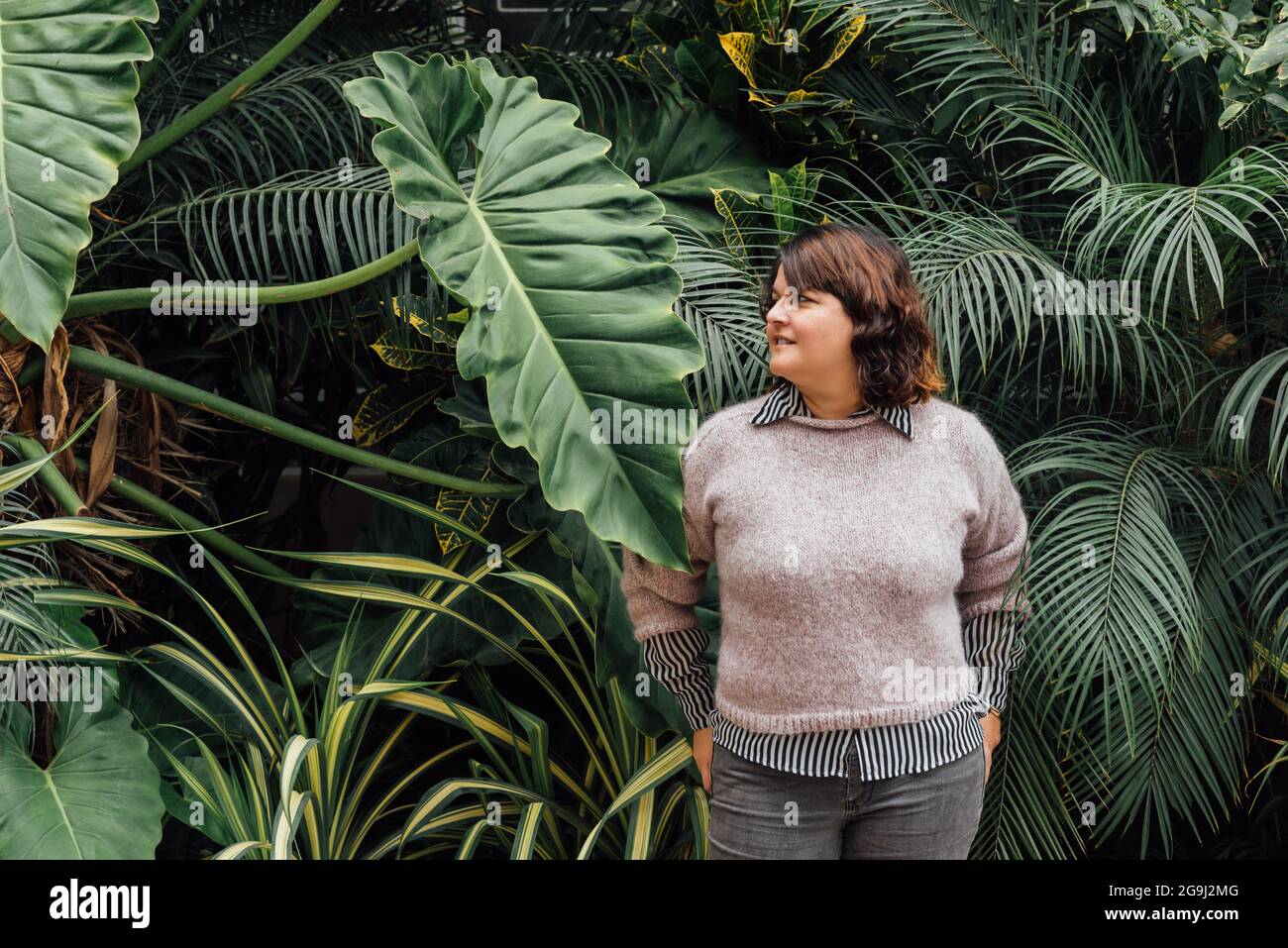 Frau mit Händen in Gesäßtaschen mit Laub Hintergrund kopieren Raum Stockfoto