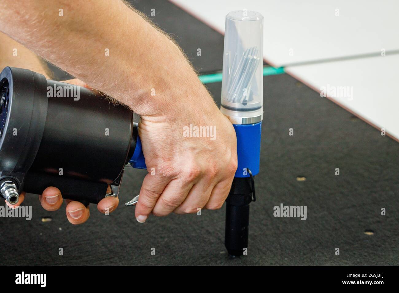 Ein Arbeiter vernietet die Löcher mit einem pneumatischen Nietmesser Stockfoto
