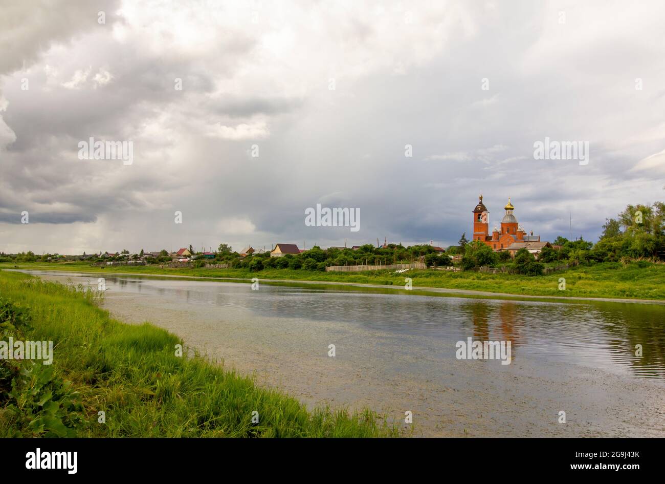 Authentische rustikale Kirche an der Küste des Flusses vor dem Hintergrund eines regnerischen Himmels. Stockfoto Authentische rustikale Kirche an der Küste des Flusses vor dem Hintergrund eines regnerischen Himmels. Stockfoto