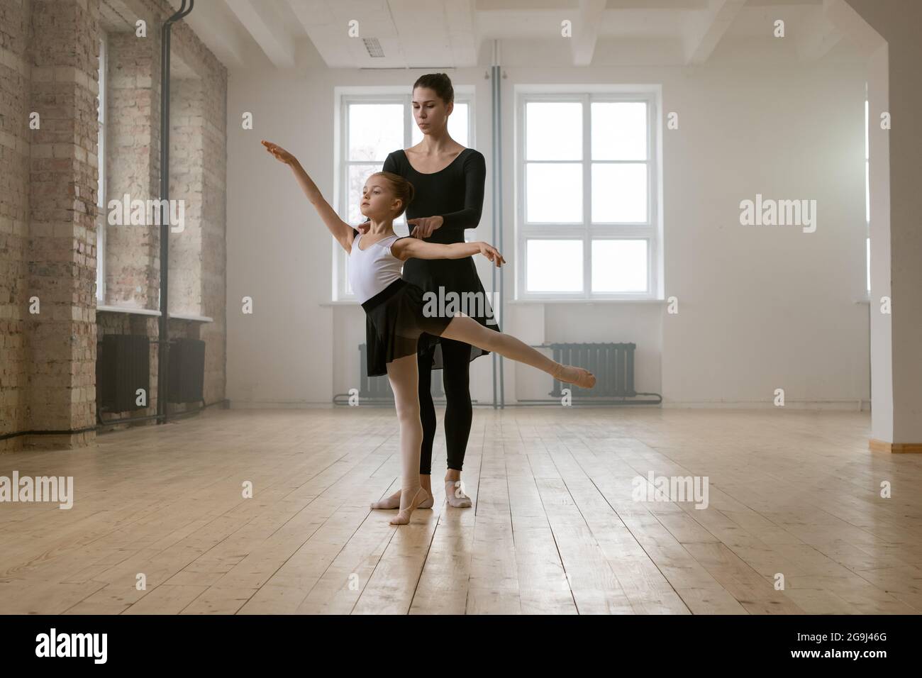 Junge Frau und kleines Mädchen stehen zusammen in der gleichen Ballett Pose und Tanz im Tanzstudio Stockfoto