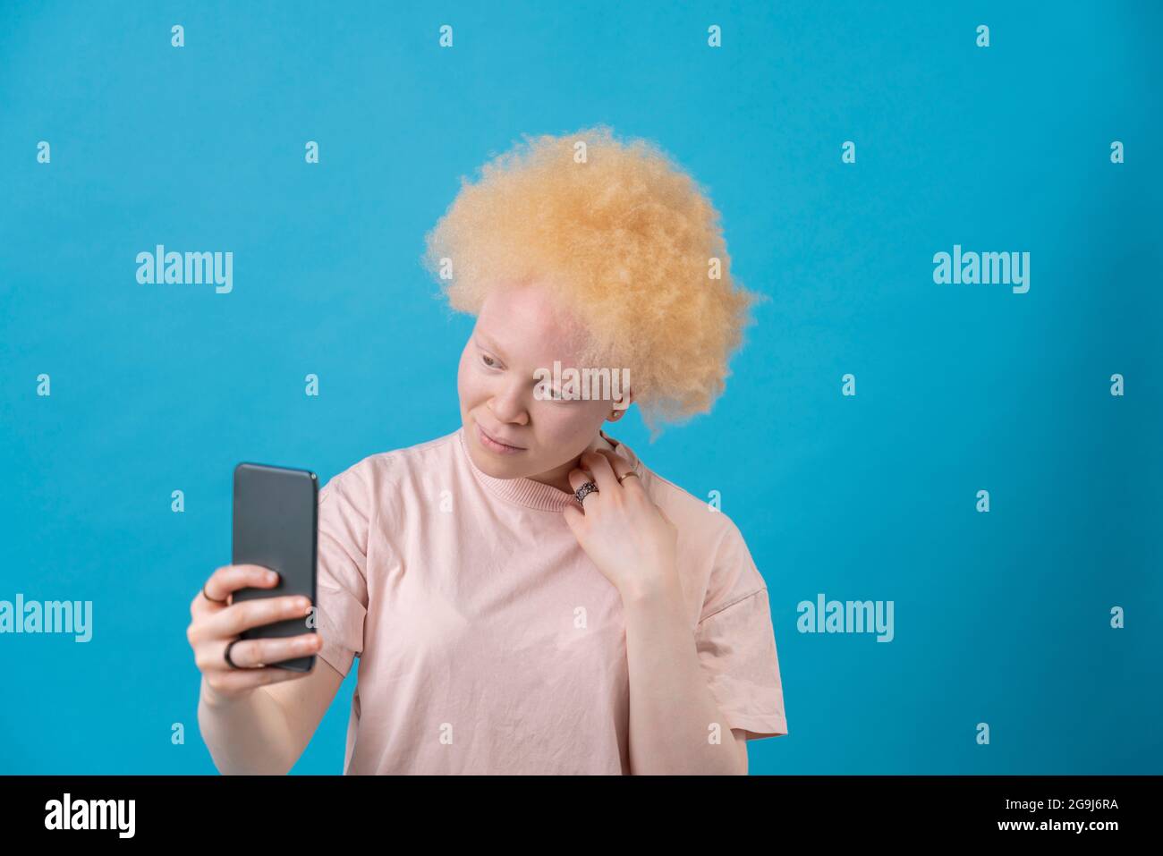 Studioaufnahme einer Albino-Frau mit Smartphone Stockfoto