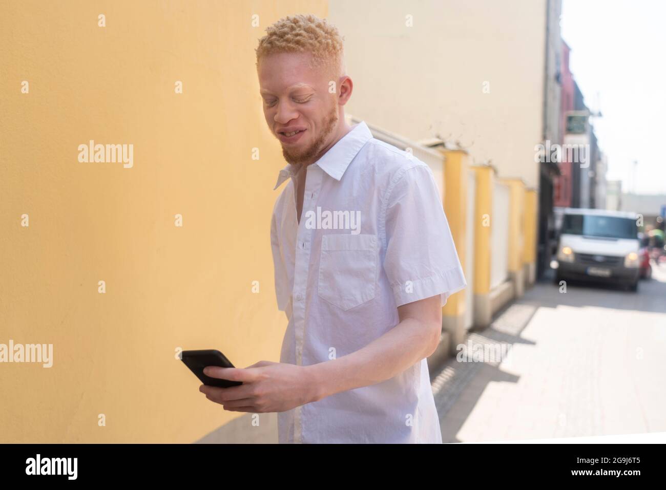 Deutschland, Köln, Albino Mann in weißem Hemd mit Smartphone Stockfoto