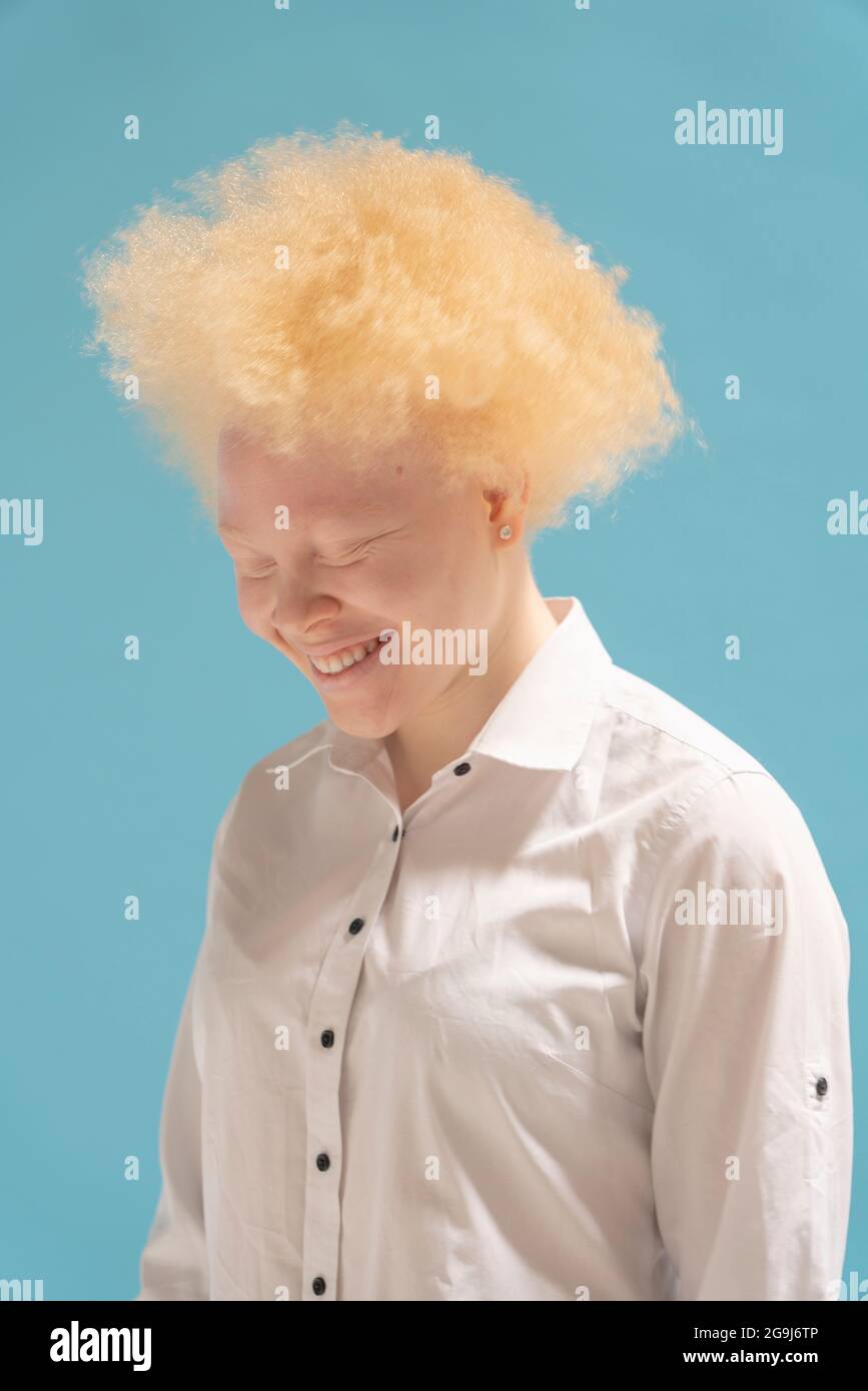 Studioporträt einer lächelnden Albino-Frau im weißen Hemd Stockfoto