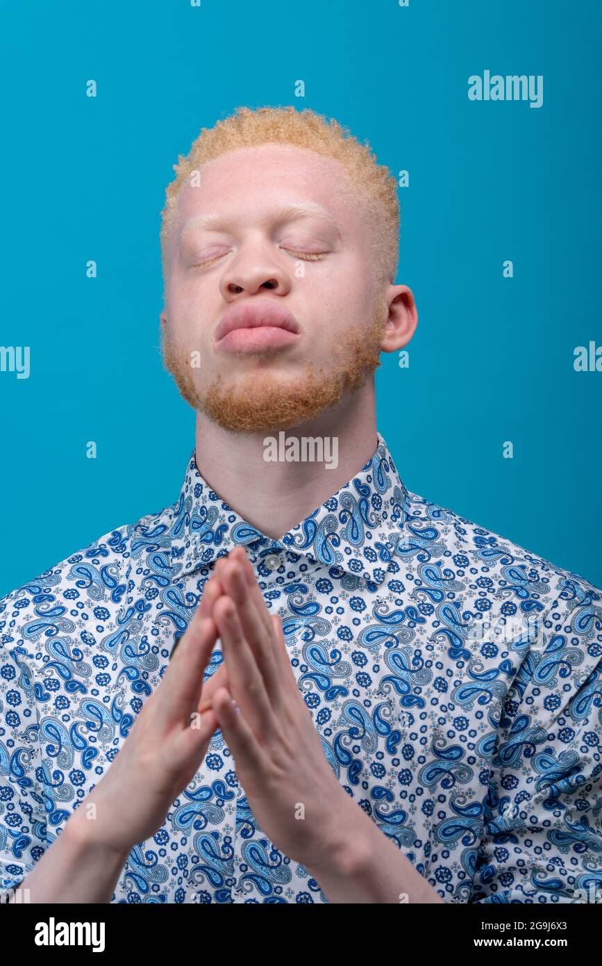 Studio-Portrait des Albino-Mannes in blau gemustertem Hemd mit geschlossenen Augen Stockfoto