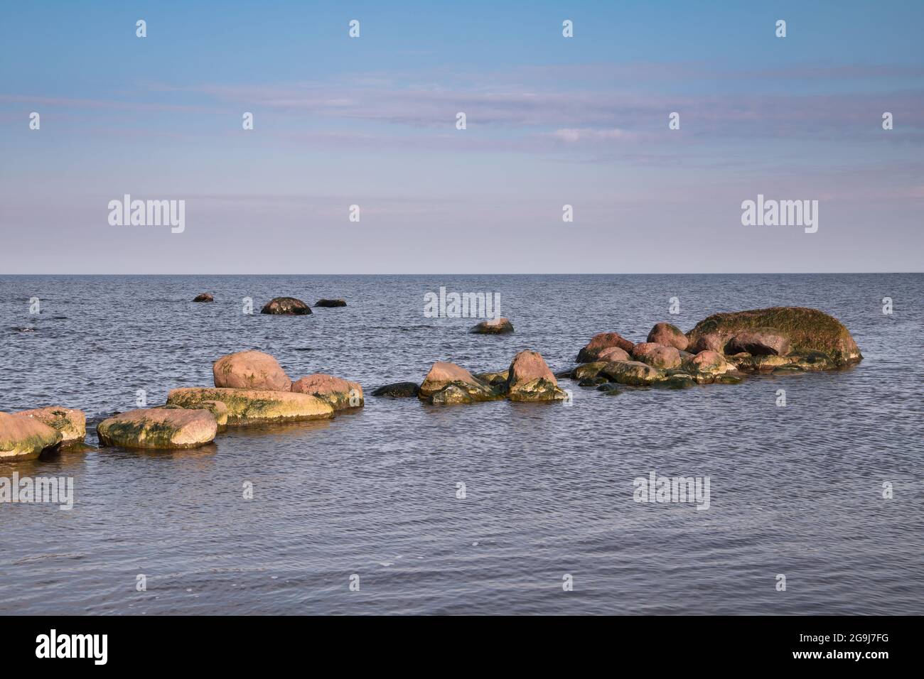 Die Küstensteine liegen in einer Reihe im seichten Wasser der Ostsee, der leeren Küstenlandschaft Stockfoto