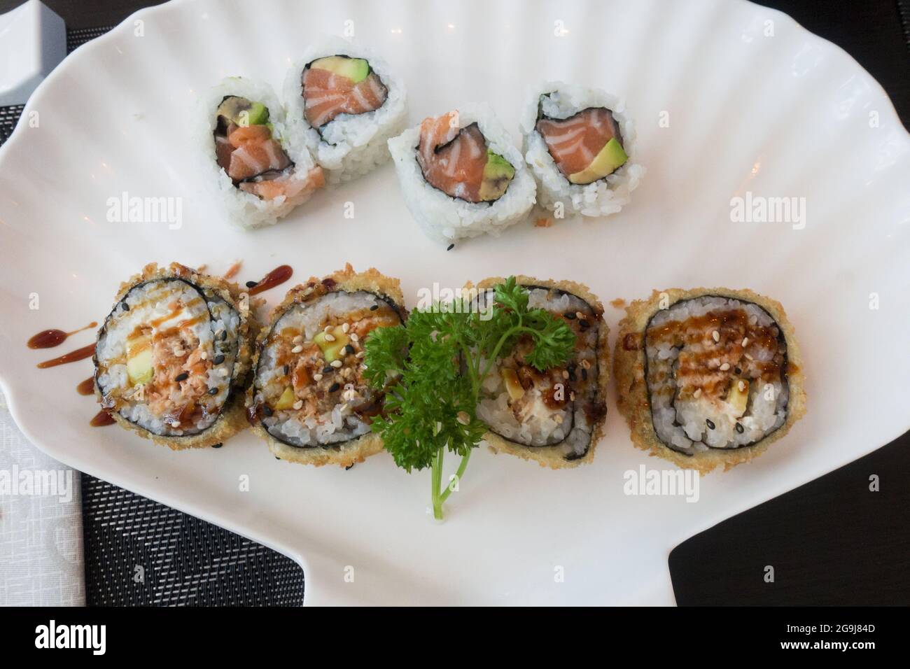 Nahaufnahme von köstlichen Sushi-Rollen auf einem schönen weißen Teller in Form eines Shels Stockfoto