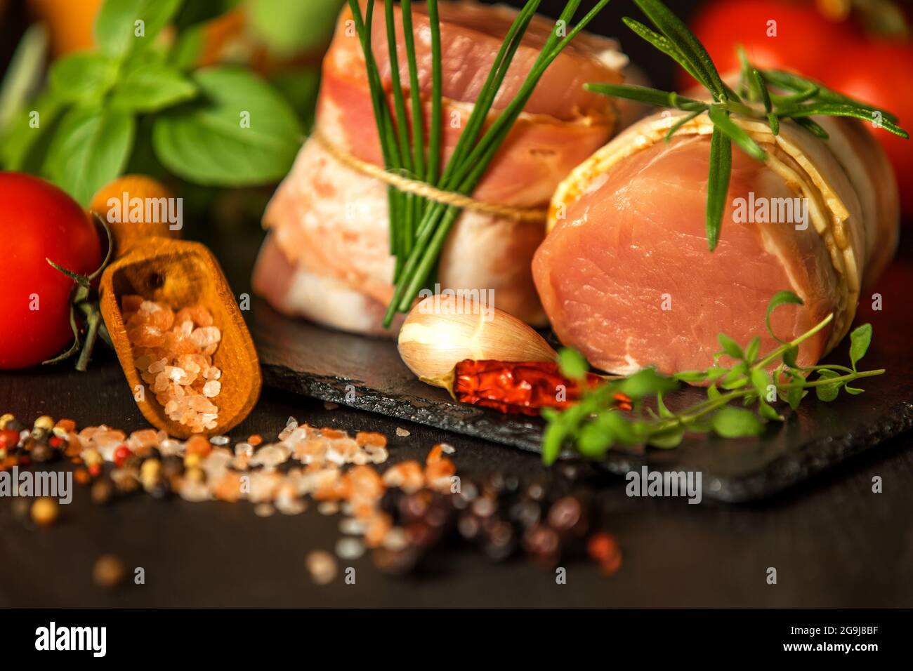 Frisches rohes Schweinefilet mit Speck auf Schiefertafel. Fleisch bereit zum Grill. Diät-Essen. Stockfoto