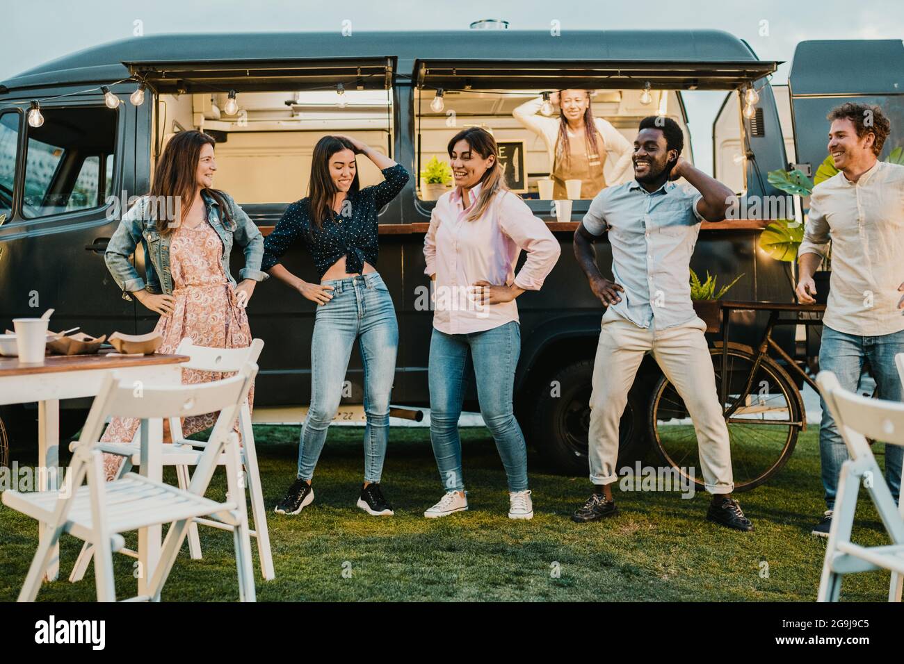 Multirassische Freunde tanzen in der Nähe von Food Truck im Park Stockfoto