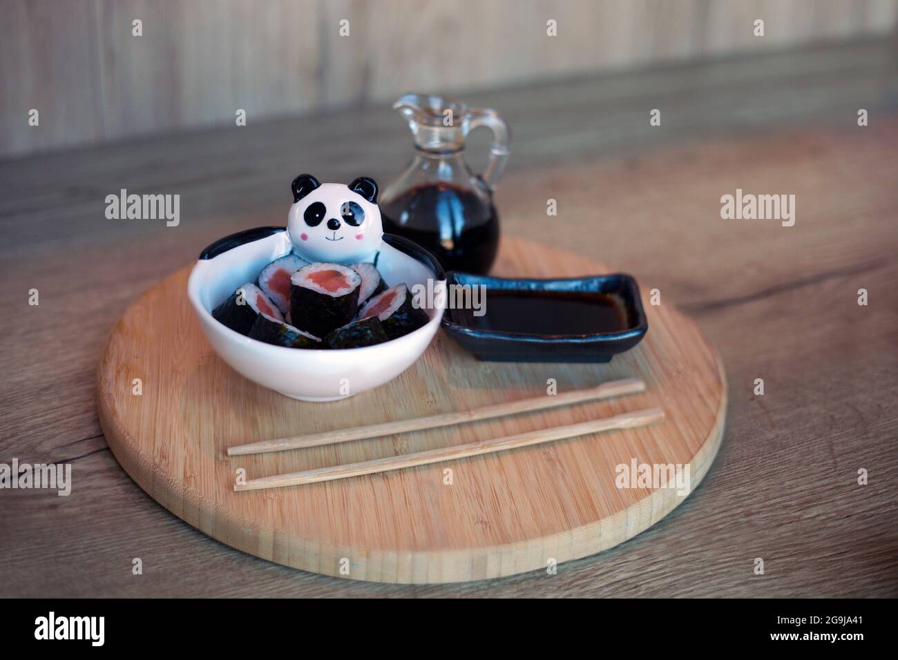 Teller mit Sushi-Rollen mit Lachs für Kinder auf Holztisch mit Essstäbchen und Soja. koreanisches Essen für Kinder Stockfoto