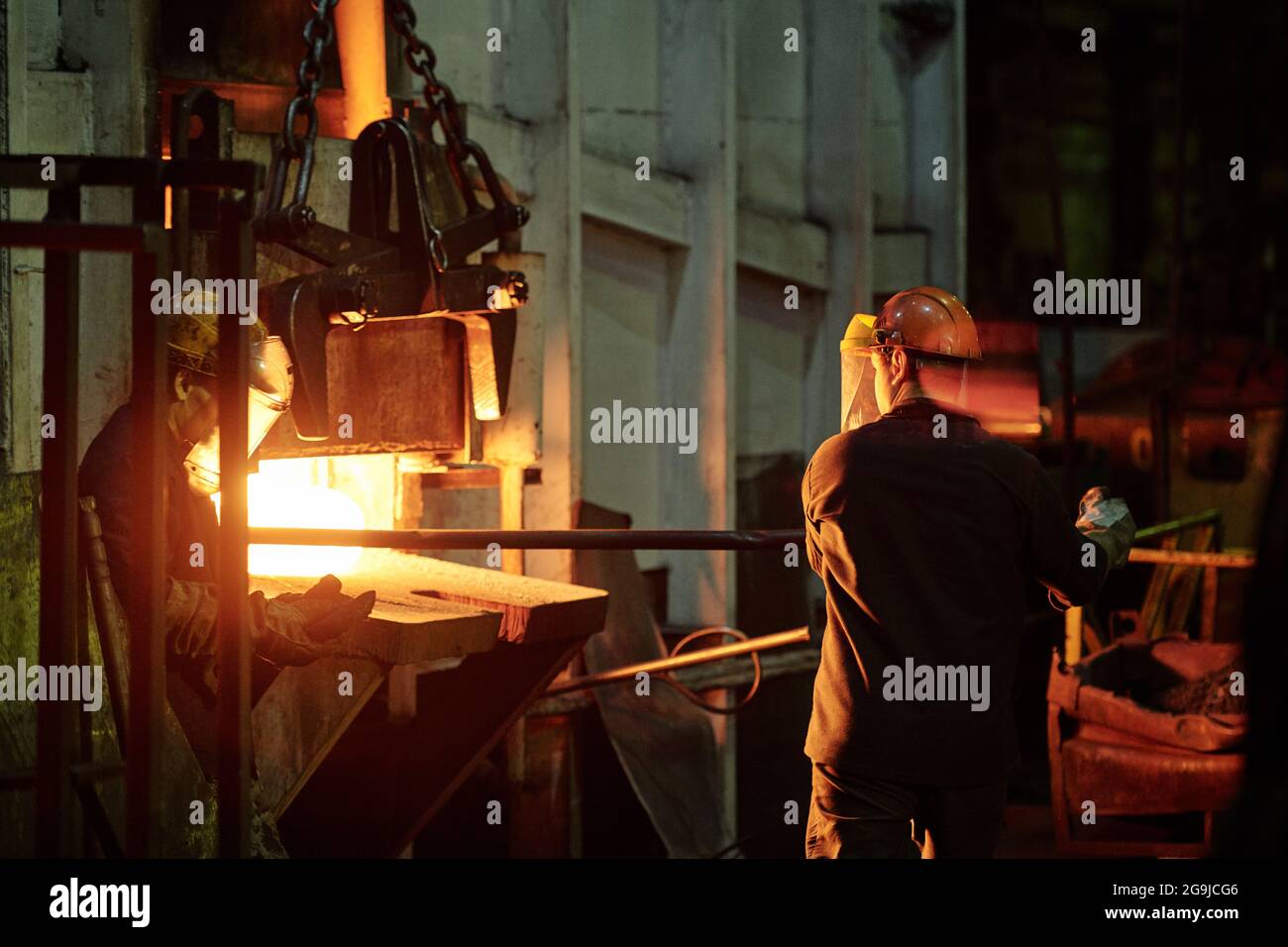 Rückansicht eines Fabrikarbeiters im Helm, der Eisenstab verwendete, während er mit Möbeln in der Industrie arbeitete Stockfoto