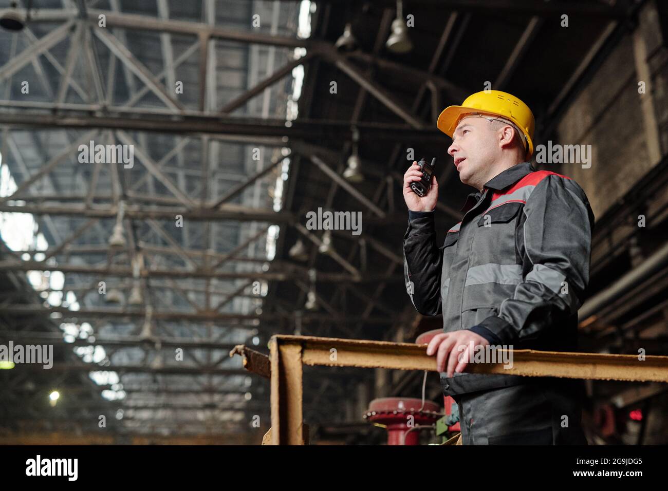 Vorarbeiter in Arbeitskleidung spricht im Funkgerät und steuert Die Arbeit in der Fabrik Stockfoto