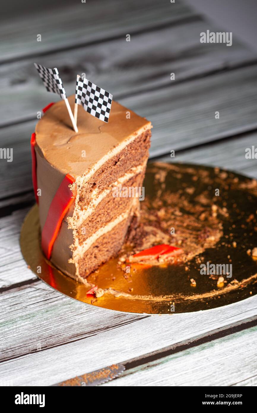 Stück eines braunen Schokoladenkuchens, verziert mit Rennflaggen auf einer Geburtstagsfeier Stockfoto