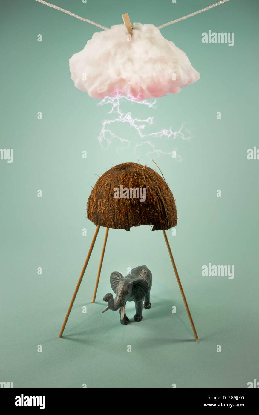 Elefant versteckt sich vor einem Sturm unter halb rissiger Kokosnuss. Kind Spielzeug Tier. Blitze schlagen aus einer Wolke, die an einem Seil hängt. Auf trendigem Pastellhintergrund. Stockfoto