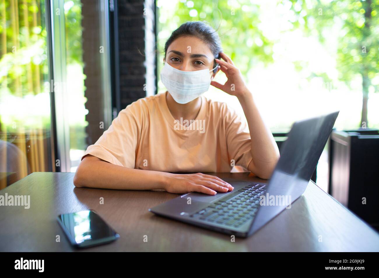 Indische Business Coaching Frau arbeitet auf ihrem Laptop im Freien mit Handy und Gesichtsmaske Stockfoto
