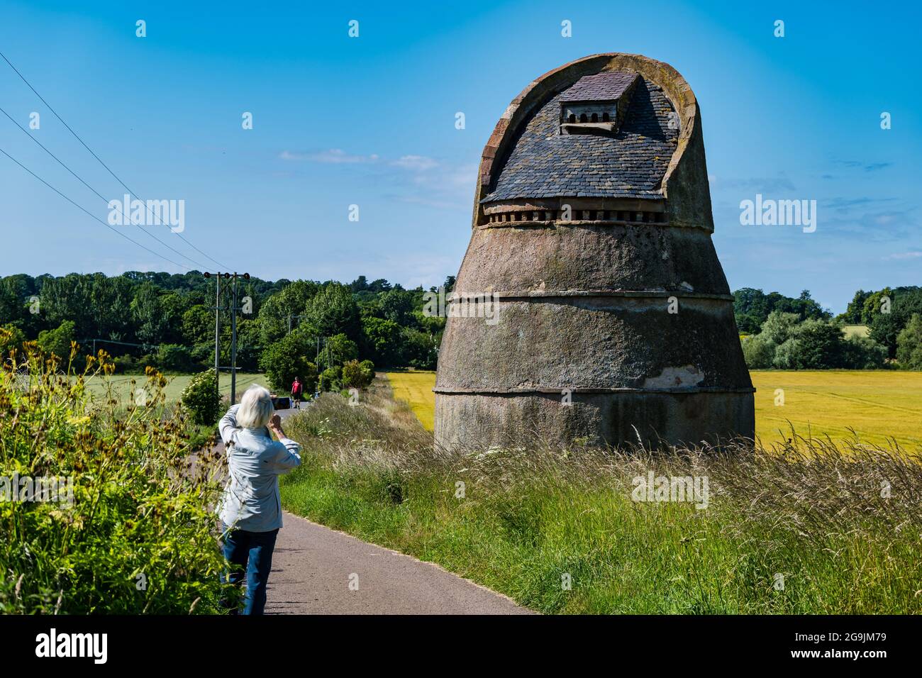 Ältere Frau, die am sonnigen Sommertag ein Foto von Phantassie Doocot, einem Bienenstock-Dovecote, macht, East Lothian, Schottland, Großbritannien Stockfoto