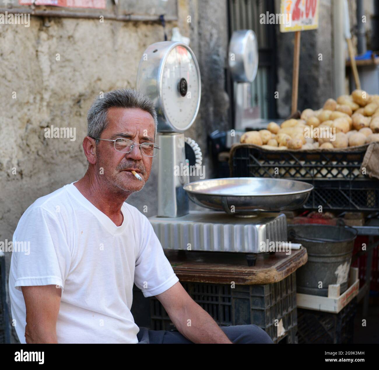 Ein italienischer Mann, der auf dem lebhaften Antignano-Markt in Neapel, Italien, eine Zigarette raucht. Stockfoto