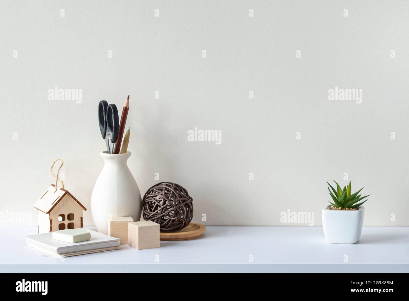 Innenausstattung mit weißem Schreibtisch oder Regal, leere Wand, Schreibwaren, dekorative Pflanze. Skandinavischer Stil. Stockfoto