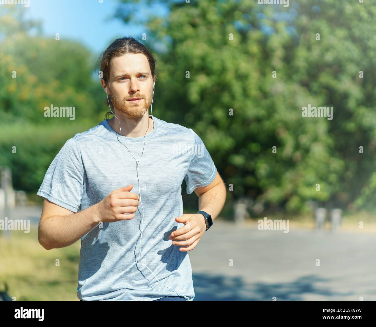 Junger, sportlicher Mann, der am Sommertag im grünen Park im Freien läuft Stockfoto