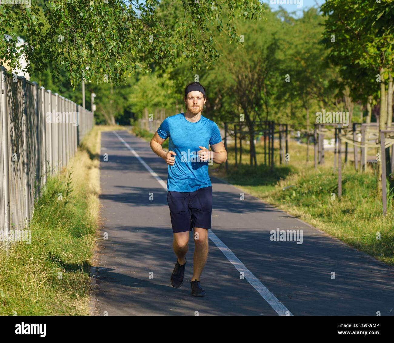 Athletischer europäer in Sportswear Joggen auf der Straße im grünen Park an schönen Sommertagen Stockfoto