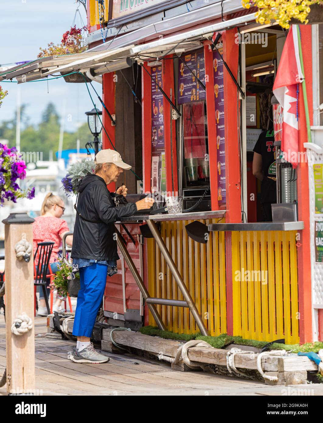 Alte pensionierte Frau, die im Straßenladen am Fisherman Wharf Markt Lebensmittel kauft. Victoria, BC, Kanada – Juli 23,2021. Straßenansicht, Reisefoto, selektiv Stockfoto