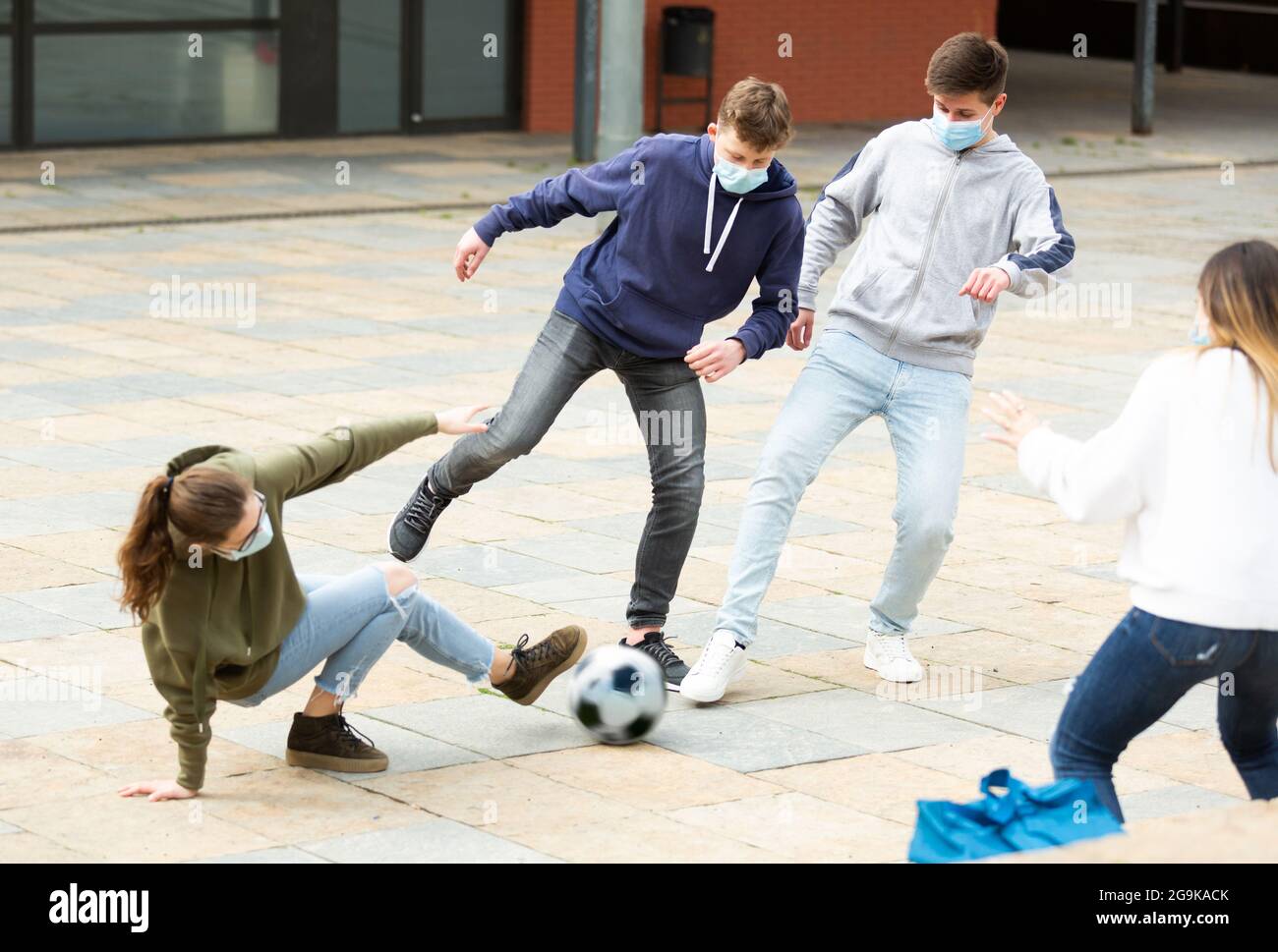 Jugendliche in Masken, die draußen Fußball spielen Stockfoto