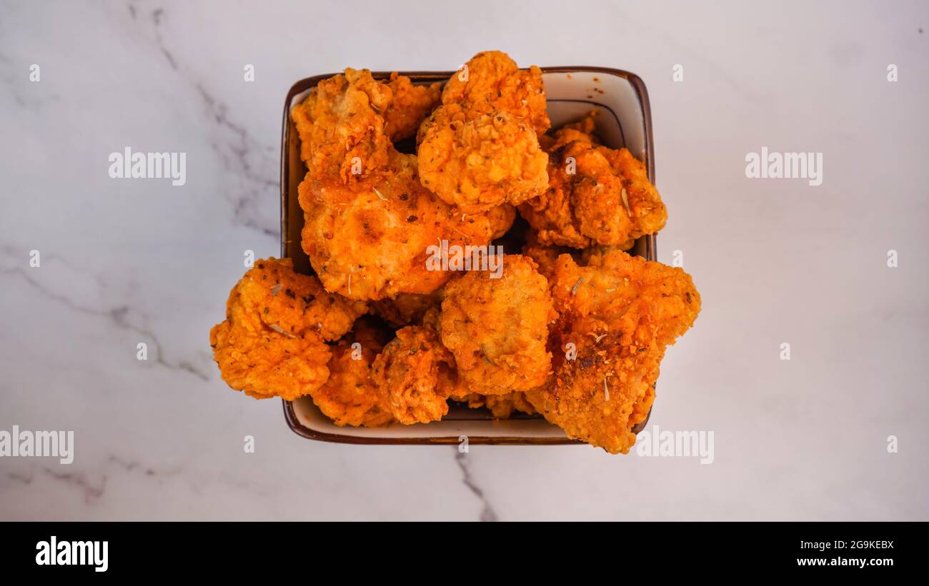 Würzige, frittierte Hähnchen-Tender Streifen knusprig in einer Schüssel isoliert auf Marmorhintergrund. Stockfoto