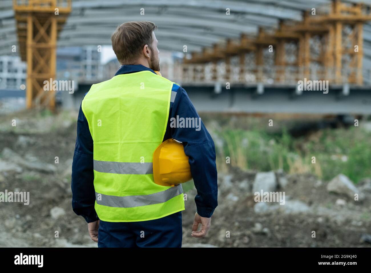Rückansicht des Baumeisters in reflektierender Kleidung, der auf der  Baustelle steht und arbeitet Stockfotografie - Alamy