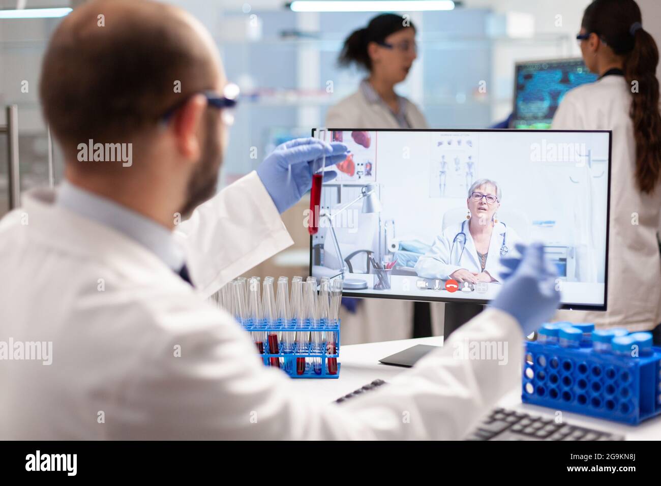 Medizinischer Experte, der während eines Online-Videoanrufs ein Gespräch über die Virusbehandlung führt, bei der Blutproben gezeigt werden. Wissenschaftler untersuchen die Entwicklung von Impfstoffen mithilfe von Hightech-Forschung in den Bereichen Behandlung, Gesundheitsinnovation und Mitarbeiterkollaboration. Stockfoto