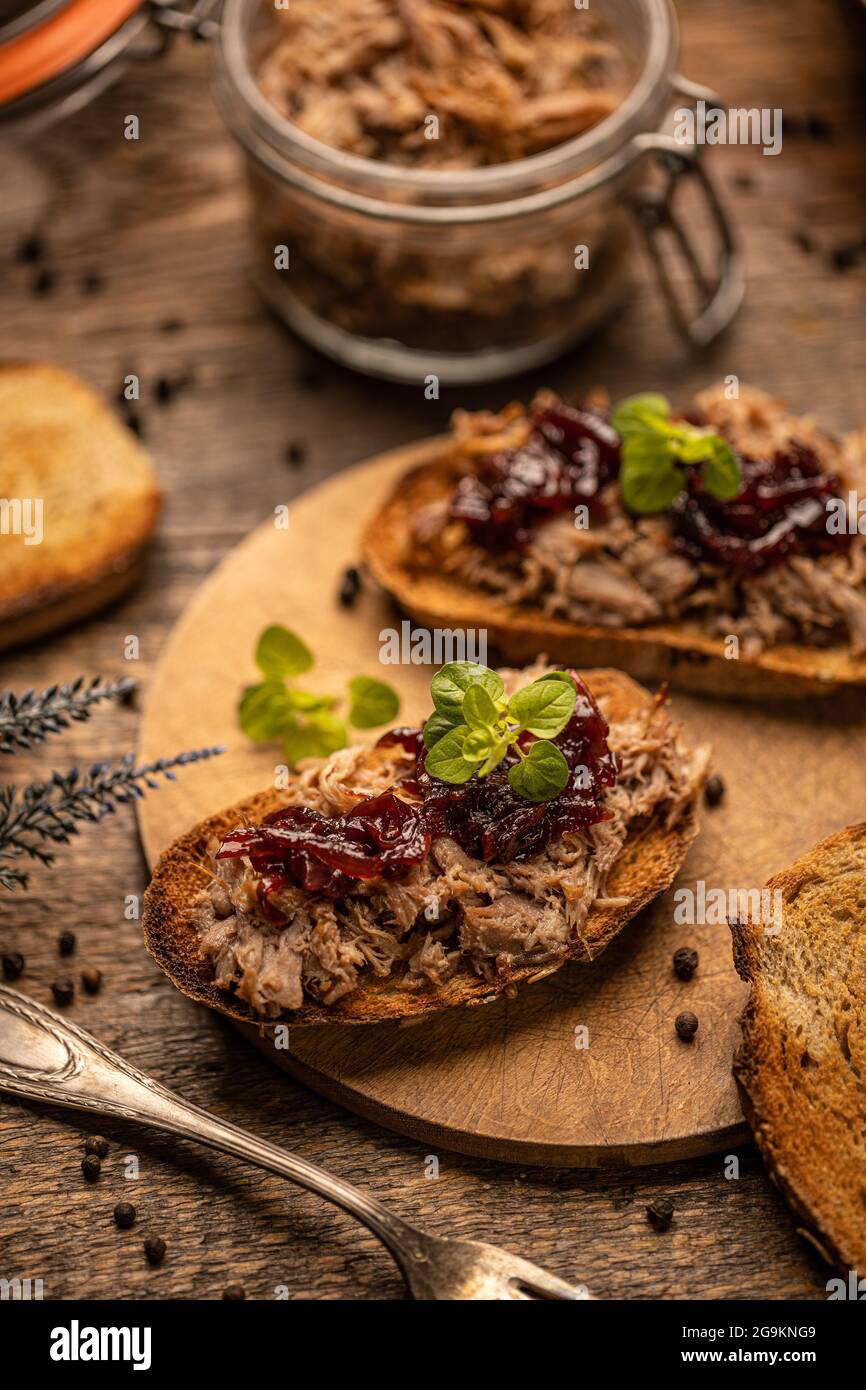 Gezogene Ente mit karamellisierten Zwiebeln auf rustikalem Hintergrund Stockfoto