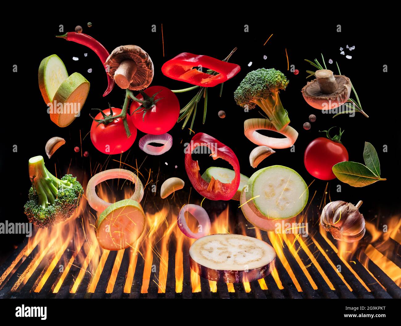 Gegrilltes Gemüse und Pilze in Bewegung fallen auf offenen Grill. Konzeptionelles Foto des Grillkochvorgangs. Stockfoto
