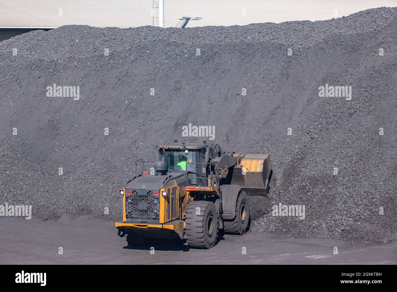 Industriekohle Produkt Rohstoff Haufen Hügel mit Schwererde Mover Fahrzeugmaschine mit Schaufel Eimer für die Beladung auf LKWs. Stockfoto