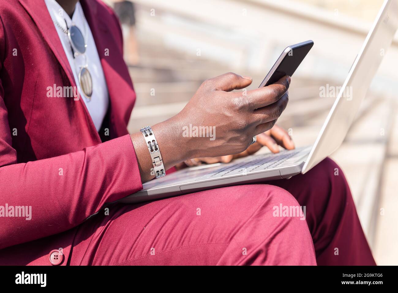 Detail der Hand eines afrikanischen Geschäftsmannes mit einem Smartphone und Computer-Laptop, Technologie und Remote-Work-Konzept Stockfoto