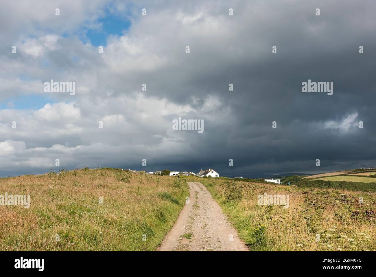 Dunkle, bedrohliche Sturmwolken sammeln sich über einen Fußweg am gesamten Point East in Newquay in Cornwall. Stockfoto