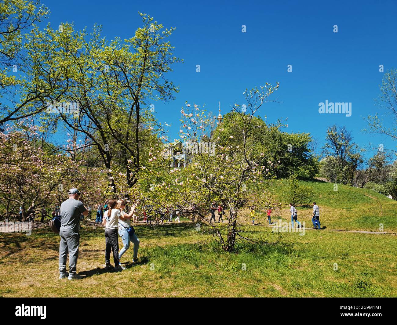 Kiew, Ukraine-30. April 2018: Ukrainer und Touristen wandern im Nationalen Botanischen Garten von Kiew. Glückliche Frau nimmt Fototo von Magnolienbaum, während Stockfoto