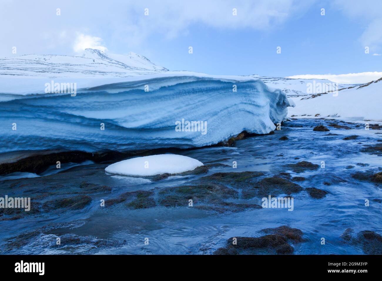 Ein Gletscherfluss bahnt sich seinen Weg durch Schnee und Eis auf der Snaefellsnes Penninsular in Westisland und enthüllt die einzelnen Schneeschichten, die BU haben Stockfoto